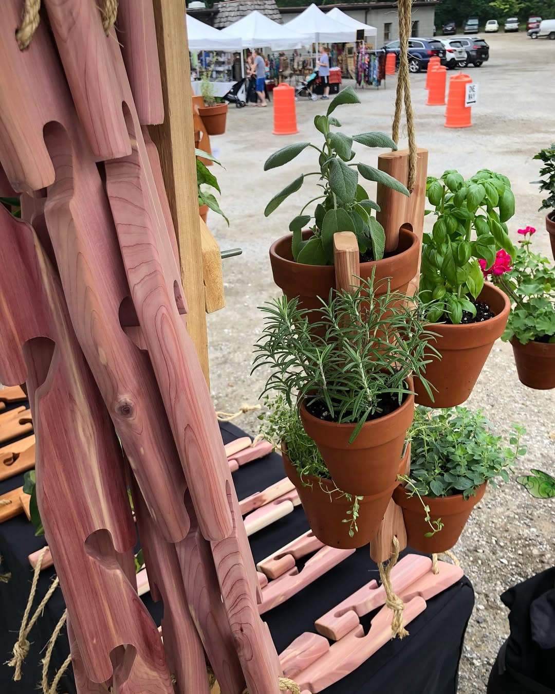 Handcrafted cedar Pot Slot hangers with herbs at a farmers market